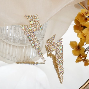 Macro shot of long lightning-shaped earrings with colorful rhinestones on silk