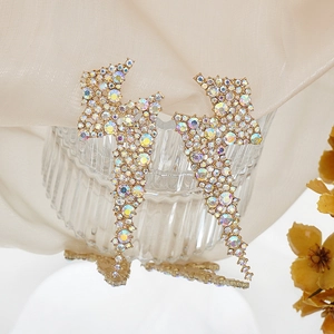 Detail of long lightning bolt drop earrings with AB crystals on golden metal base