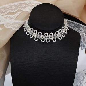 Dettaglio di un girocollo di perle bianche fatto a mano su un supporto nero elegante