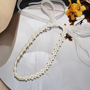 Detail of elegant pearl necklace and organza ribbon displayed on a mirror with soft shadows
