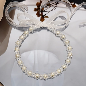 Detail of faceted crystal beads and faux pearls with a white organza bow ribbon