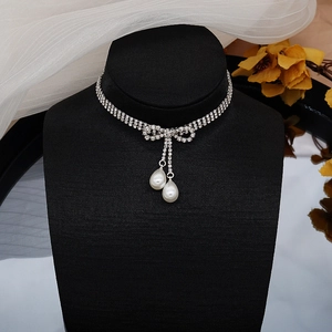 Detalle de gargantilla con lazo de diamantes de imitación plateados y gotas de perlas