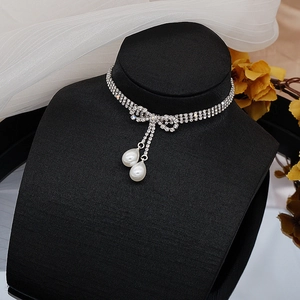 Detalle de gargantilla de tres filas de diamantes con lazo y colgantes de perlas