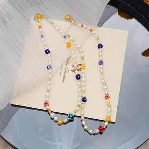 Détail d'un collier de perles d'eau douce avec fleurs en verre et pendentif champignon
