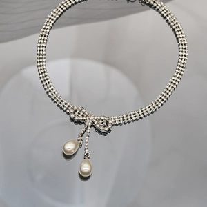 Primer plano del collar con lazo de diamantes de imitación y elegantes perlas de gota