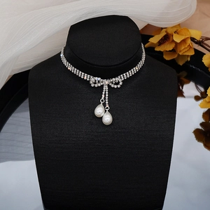 Gargantilla plateada elegante con lazo de diamantes y perlas de gota en maniquí negro