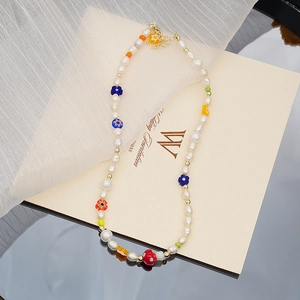 Collier artisanal avec perles d'eau douce, breloques florales colorées et accents dorés