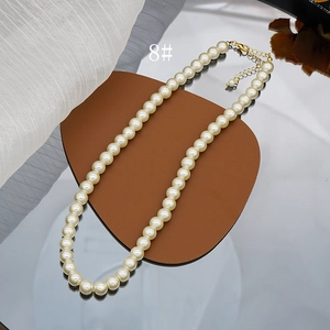 Detailed macro view of the cream glass pearl necklace with gold-plated lobster clasp
