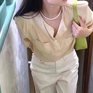 Detail of elegant glass pearl necklace paired with a light yellow V-neck casual shirt