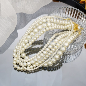 Elegant multi-layer gradient pearl necklace with gold clasp on reflective glass