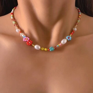 Détail d'un collier de perles colorées avec perles baroques et fleurs en acrylique