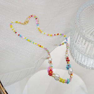 Détail d'un collier de perles colorées avec fleurs sur fond de tissu blanc doux