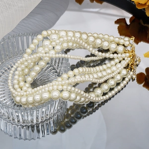 Macro detail of multi-layer glass pearl necklace with gold lobster clasp on glass tray