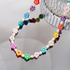 Détail d'un collier de perles et fleurs en argile polymère colorée reflété sur miroir