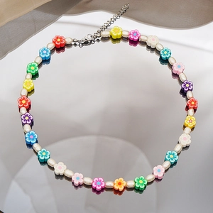 Détail de perles fleurs en pâte polymère colorée et perles baroques sur un collier