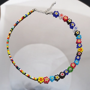Détail de perles de fleurs en verre millefiori et design de collier perlé asymétrique