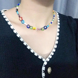 Détail d'un collier ras de cou en perles colorées avec fleurs en verre faites main