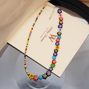 Gros plan d'un collier à fleurs en perles colorées sur un fond de carte d'invitation