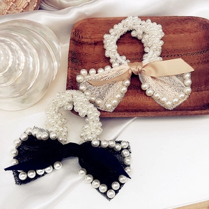 Detailed shot of elastic pearl hair scrunchies with elegant ribbon bows and lace trim