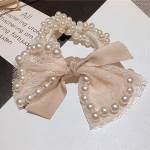 Close-up of pearl elastic hair tie with cream satin bow and lace texture details