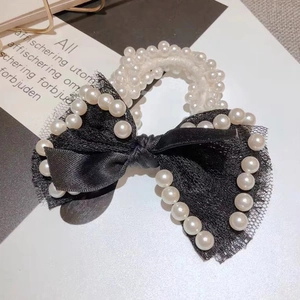 Close-up of elegant black lace and ribbon hair scrunchie with white pearl accents