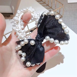 Detailed close-up of pearl elastic hair tie with black lace bow and satin ribbon finish