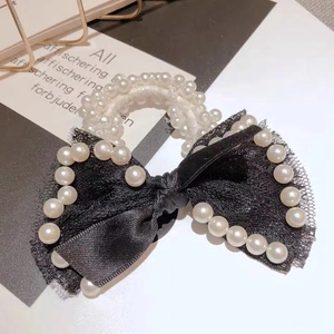 Close-up of black lace bow hair tie with elegant white pearls and elastic band