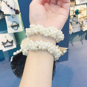 Detail of white faux pearl hair ties with black lace and beige ribbon bow accents