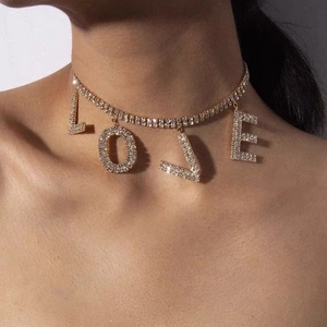 Detalle del collar choker dorado con colgantes de letras LOVE y brillantes strass