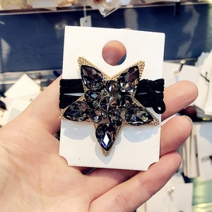 Close-up of black elastic hair tie with large crystal-studded gold star pendant