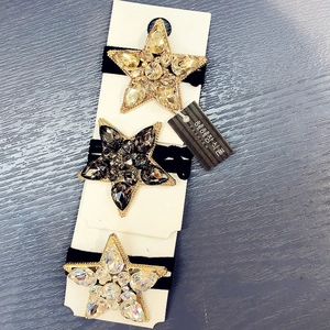 Detailed view of three crystal star hair ties in gold, grey, and white on a display card