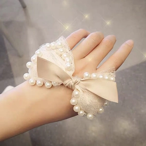 Detail of cream silk bow hair scrunchie with lace lining and faux pearl edges