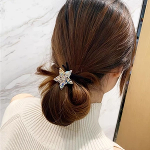 Close-up of a sparkling crystal star hair tie on a woman's brown low bun hairstyle