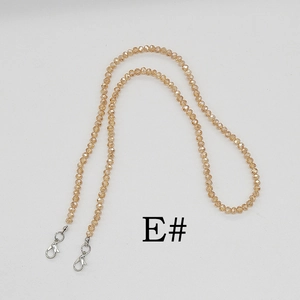 Détail macro d'une chaîne en perles cristal doré champagne avec des fermoirs mousquetons