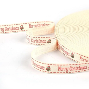 Close-up of beige cotton ribbon with red Merry Christmas text and owl pattern