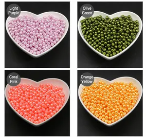Assorted colorful craft pearls in purple, green, pink and orange in a heart ceramic bowl
