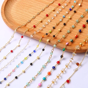 Macro detail of 18k gold plated chains with colorful beads and crystal charms
