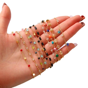 Hand holding assorted 18k gold plated beaded bracelets with colorful drip oil stones