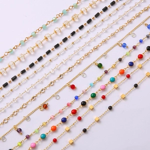 Detailed flat lay of 18k gold plated chains with colorful enamel stones and crystal beads