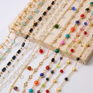 Close-up of 18k gold plated chains with colorful enamel beads and geometric accents