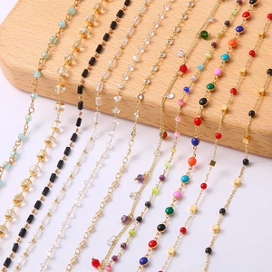 Variety of 18k gold plated jewelry chain beads with colorful stones on wooden stand