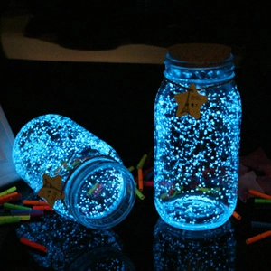 Dettaglio di bottiglie dei desideri in vetro con ghiaia blu luminosa nell'oscurità