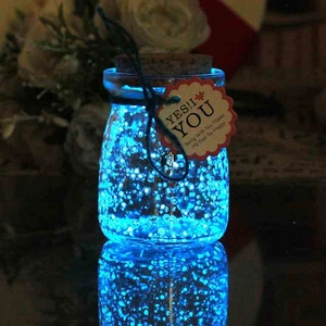 Pietre luminose blu in una bottiglia dei desideri con etichetta decorativa