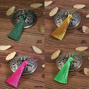 Detailed view of four colorful 8cm silk tassels on vintage wood background