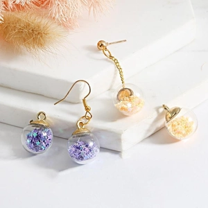 Macro detail of star sequin filled glass ball pendants with golden earring hooks
