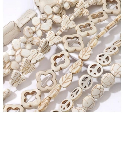 Vista macro de cuentas de turquesa blanca en forma de mariposa y hoja para joyería DIY