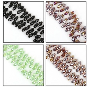 Detailed macro of 6x12mm faceted glass beads in black, purple, green, and brown colors