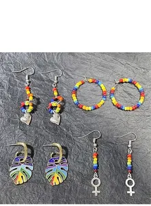 Detail showing rainbow beaded hoop earrings and heart-shaped pendants on dark paper