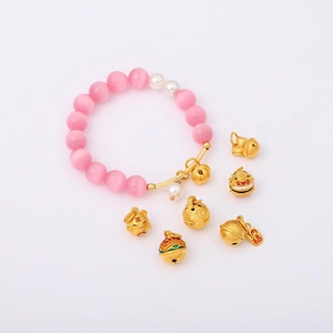 Dettaglio del bracciale di perle opache rosa con ciondoli a forma di tigre e campanellini
