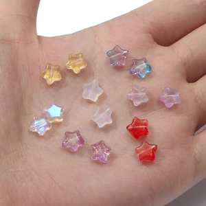 Colorful star-shaped glass beads for DIY jewelry making held in a hand for scale